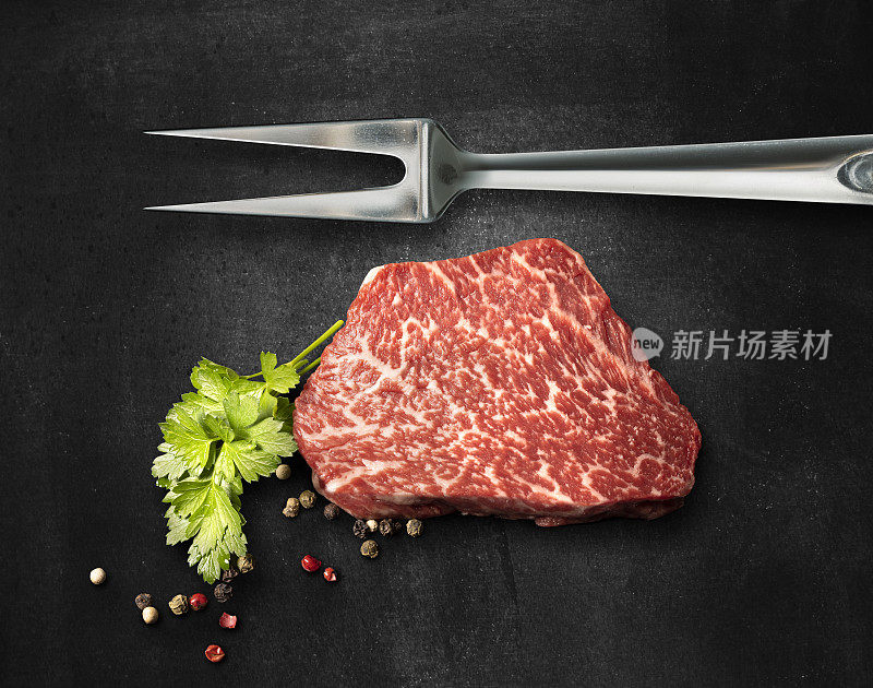 用叉子叉着的神户牛肉片在黑色背景上