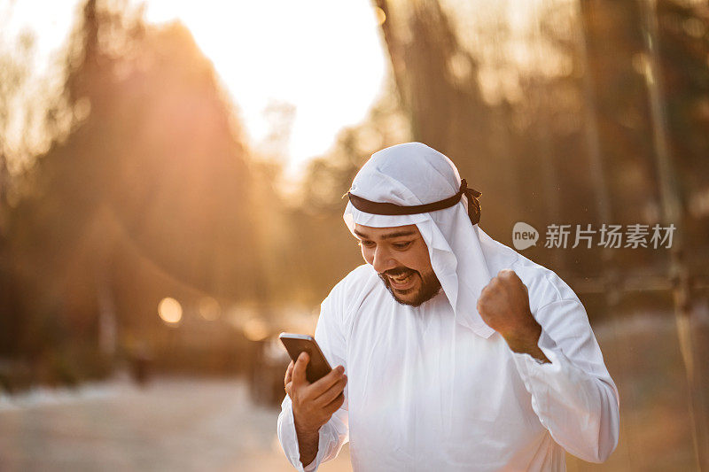 阿拉伯沙特兴高采烈的商人正在电话上查看电子邮件
