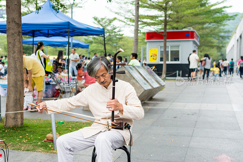 中年中国街头音乐家在中国深圳中央公园演奏中国传统乐器-二胡(中国小提琴)