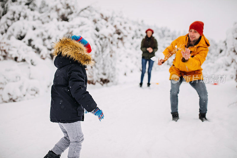 在一个美丽的冬天，年轻快乐的家庭一起在户外玩雪