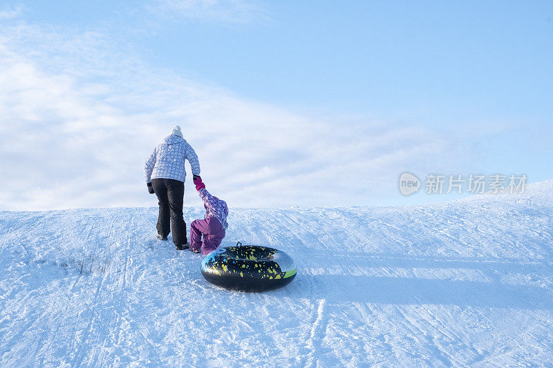 家人在冬天度假。一个女人和一个5岁的白种人孩子在爬山。