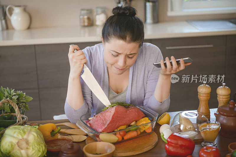 女人在厨房做饭(牛肉和智能手机)