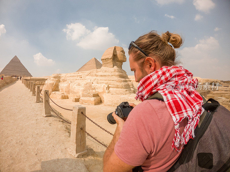 一名男性游客在埃及拍摄金字塔和狮身人面像