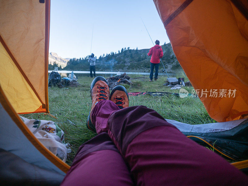 POV的女人露营在高山附近的湖，日出