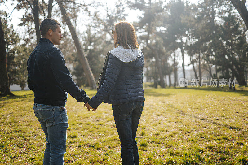 年轻的情侣在城市公园散步，一起享受美丽的大自然