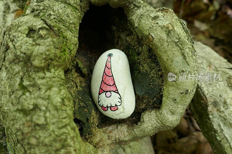 可爱的侏儒画在善良的岩石上，藏在树洞里