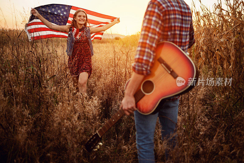 一个欢快的年轻女子拿着美国国旗跑向她的男友