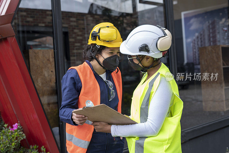 两个拉丁女人在施工的过程中，他们领导观察计划