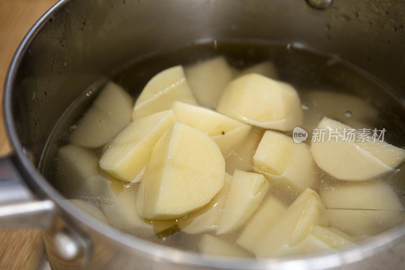 近距离拍摄去皮的土豆在锅中的水，准备煮沸