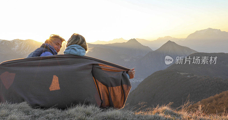 成熟的夫妇在日出时在山脊上放松