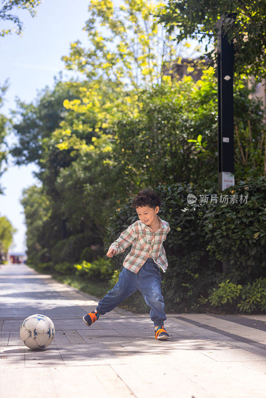 一个小男孩在院子里踢足球