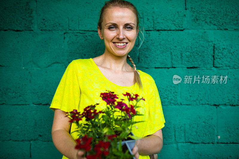 一个漂亮的女人在绿色的墙前捧着花