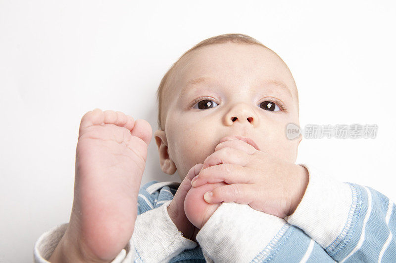 五个月大的男婴把脚放进嘴里