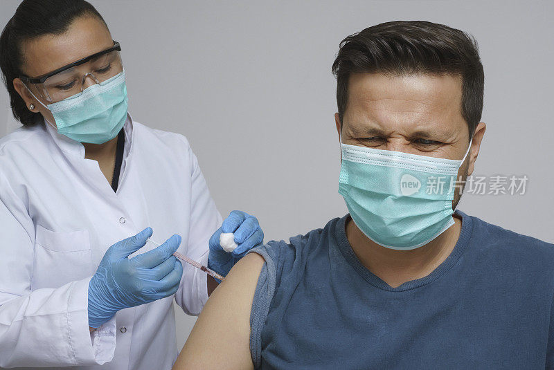 身穿防护工作服的女护士向患者手臂注射Covid-19疫苗