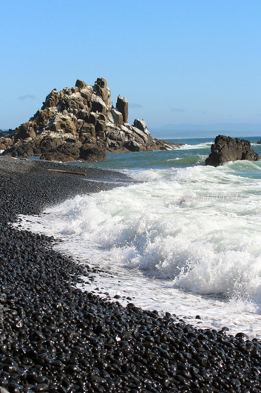 俄勒冈州海岸的雅奎纳头灯塔风景区，海浪撞击着鹅卵石海滩的岩石