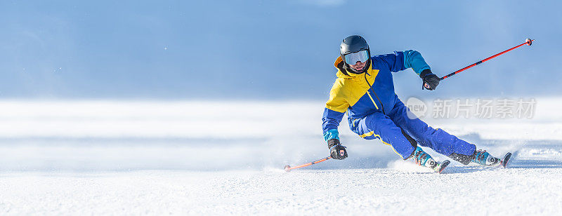 一名年轻的滑雪者在高山斜坡上展示了一种极端的雕刻滑雪风格。他正在早晨整洁的滑雪道上滑雪。