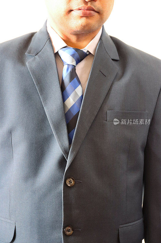 难以辨认的商人的特写图像穿着聪明，蓝色西装白色，纽扣领衬衫和蓝色格子领带，摆着看着相机，四分之三的肖像