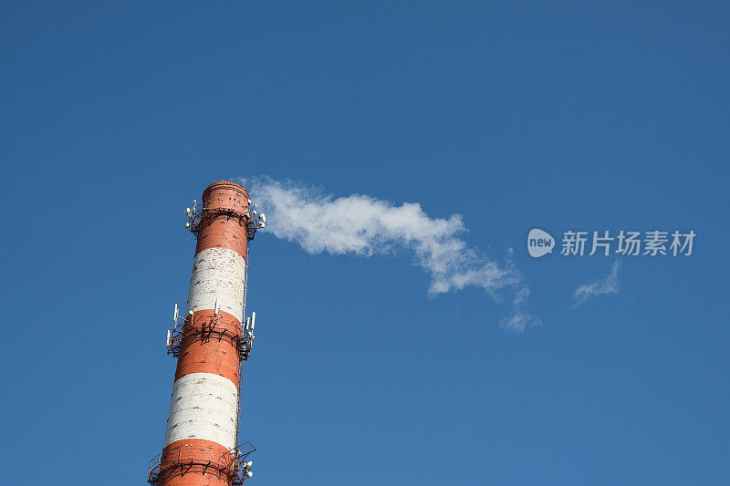 工业烟囱里冒出的滚滚浓烟随风飘过晴朗的天空