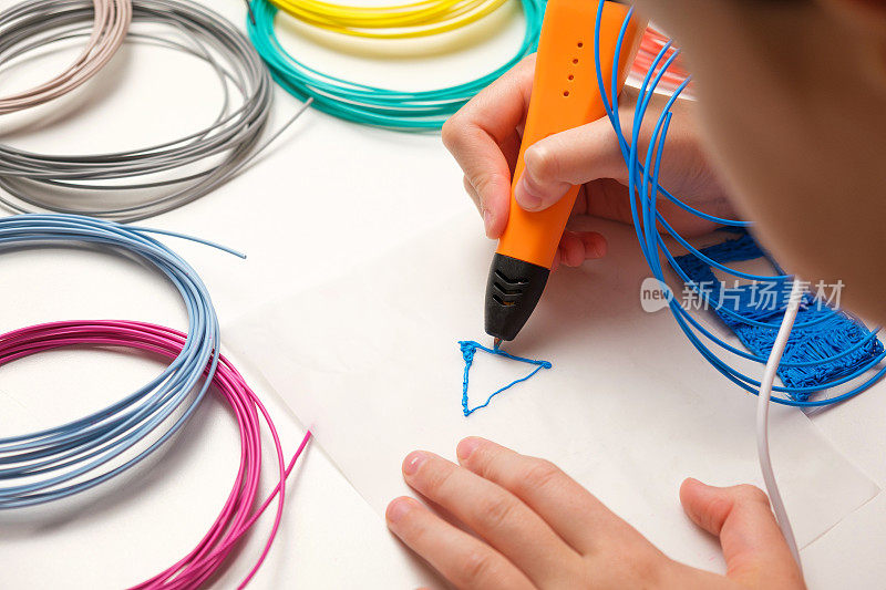 少女使用3d钢笔。彩色塑料丝丝印花。用3D笔画圣诞三重奏。艺术品、机器人技术。蒸汽,遏制教育。现代技术。在家里学习。