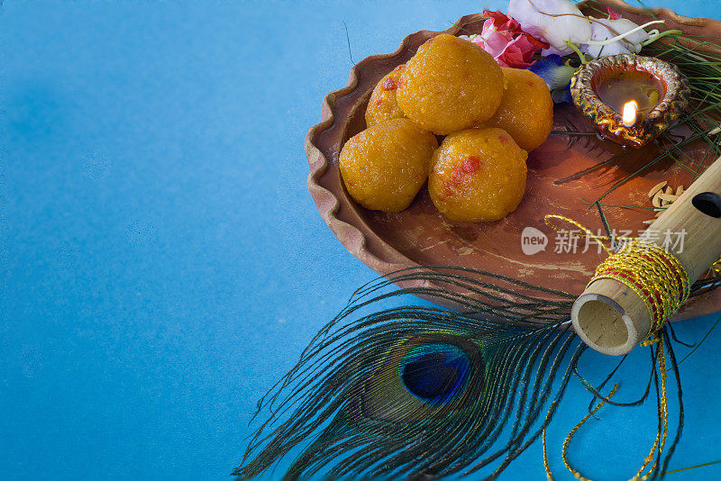 在janmashtami节日庆祝期间，用孔雀羽毛装饰的竹笛象征印度教神克里希纳与甜蜜的拉杜，diya和鲜花。