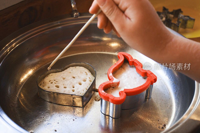 孩子的手在煎锅里塑造自制松脆饼