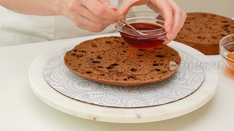 女人用手把糖浆倒在巧克力蛋糕上。一步一步讲解巧克力蛋糕的制作方法，近距离展示烘焙过程
