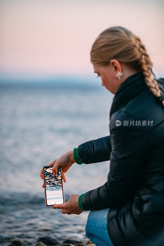 年轻女子在海滩上用智能手机拍照