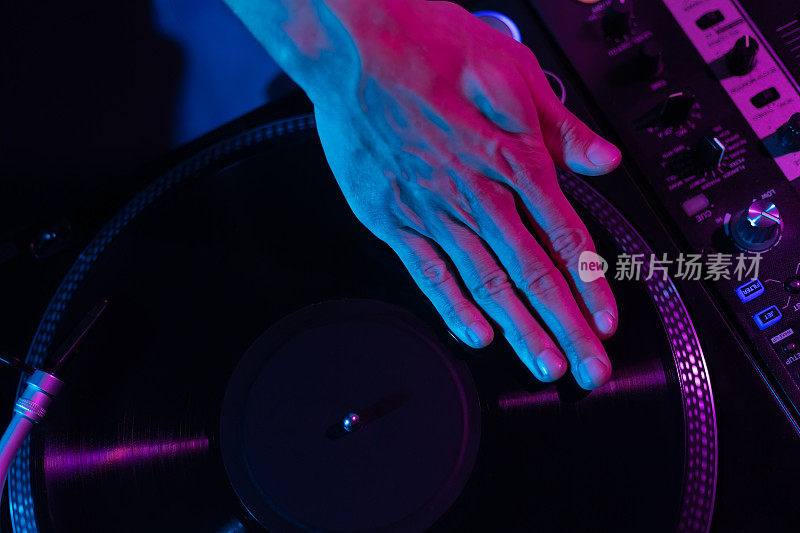 嘻哈DJ在转盘上刮黑胶唱片。俱乐部唱片师在派对上混音唱片，专注在手