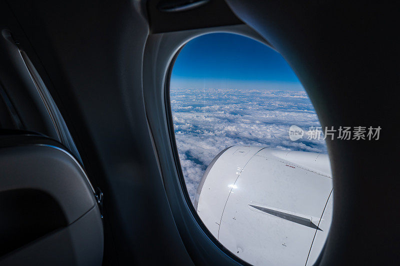 商用飞机喷气发动机。从船舱的窗户看，蓝天，下面是阴云，没有人