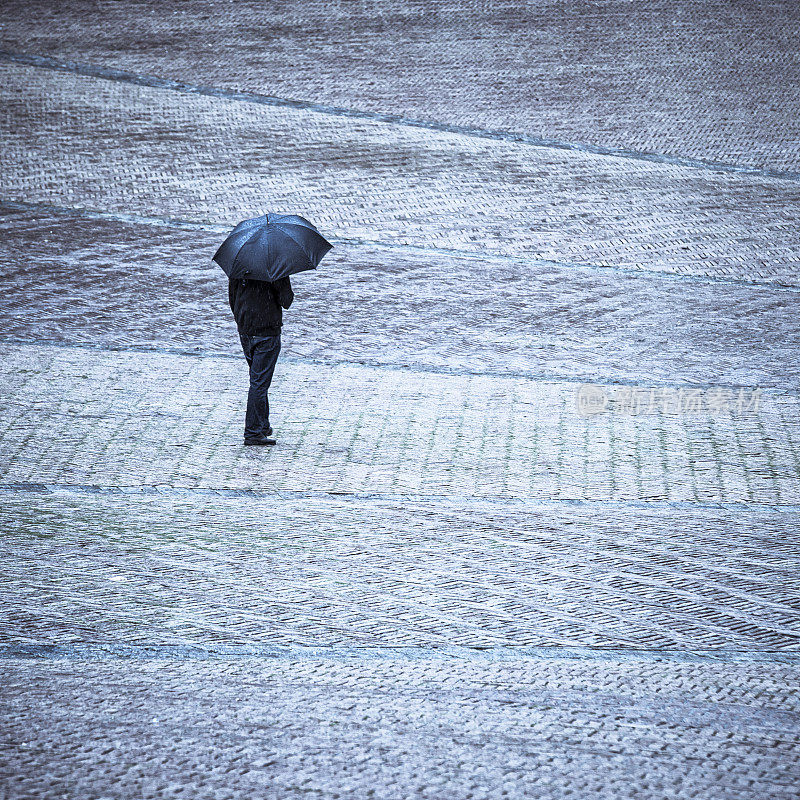 孤身一人撑着伞站在雨中