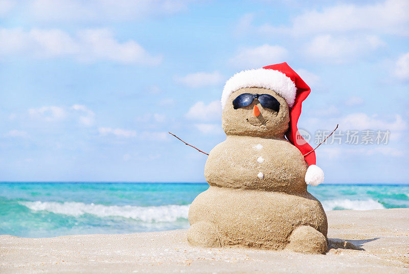 在沙滩上，戴着圣诞帽的圣诞雪人