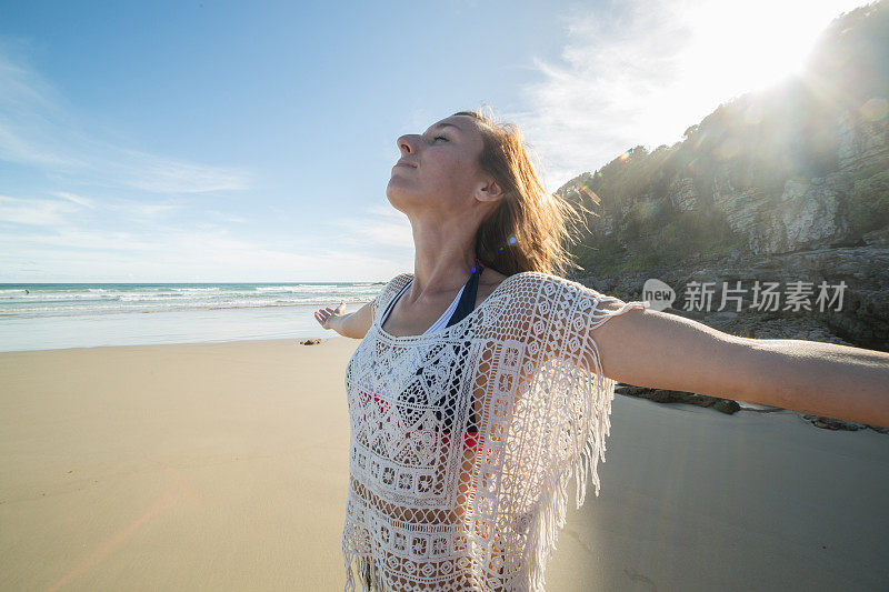 一名年轻女子在日出时在海滩上休息