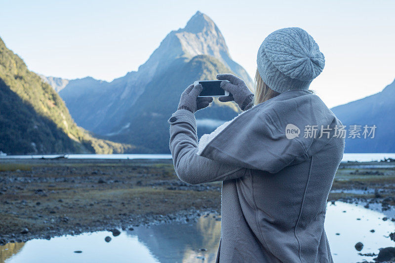 年轻女子用手机拍摄山景