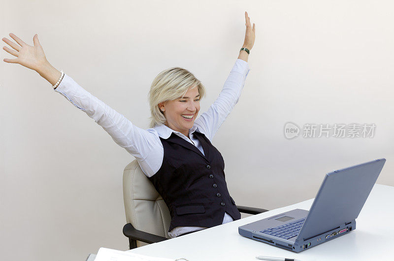 幸福微笑的金发女商人举起了手提电脑