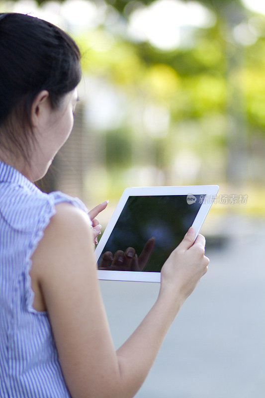 亚洲女性使用iPad的后视图