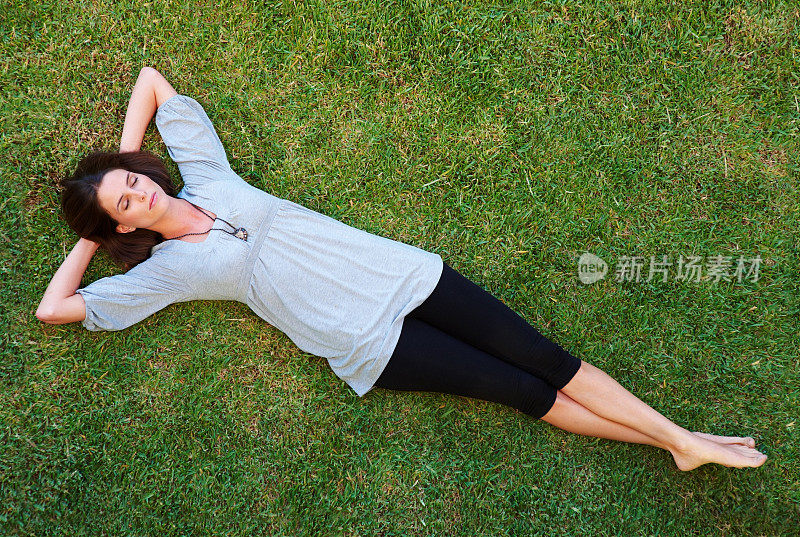 年轻漂亮的女人在草地上休息