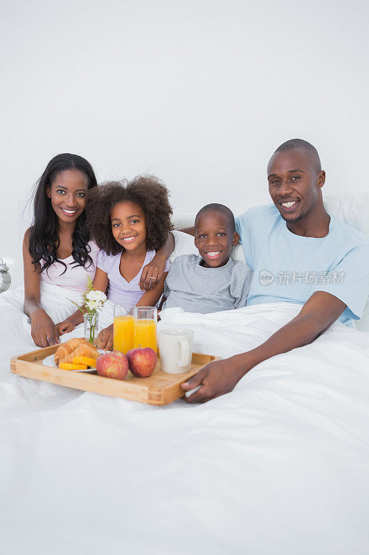 欢乐的家庭在床上看着摄像机吃早餐