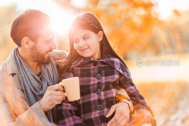 日落时分，父亲和女儿在公园里交流。