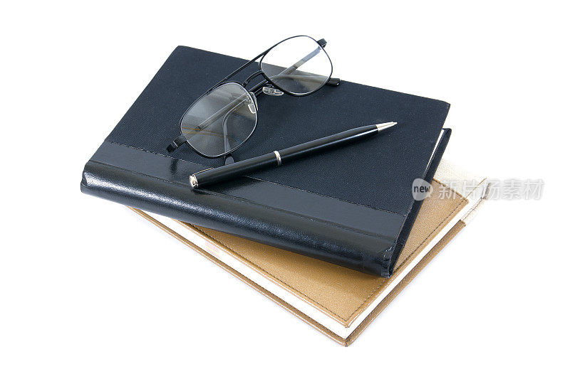 钢笔、书籍和眼镜孤立在白色的背景上