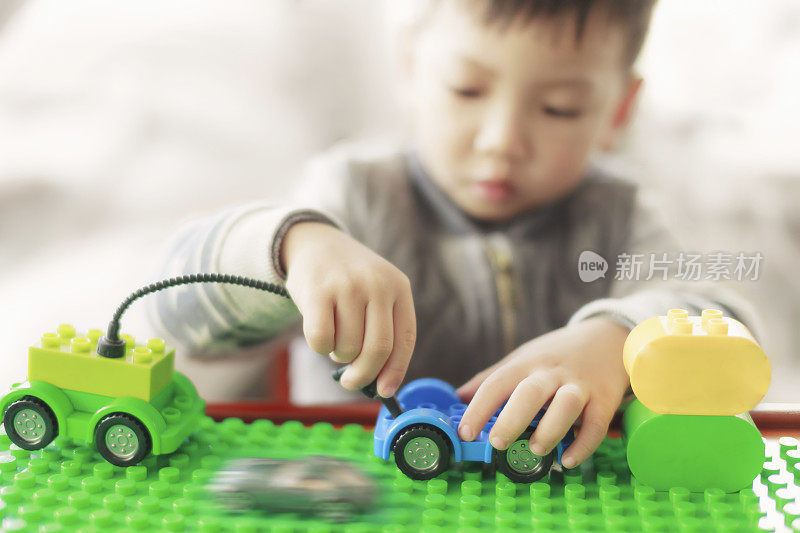 小孩子在室内玩五颜六色的塑料积木。一个喜欢建筑和创造的小男孩。选择性关注玩具