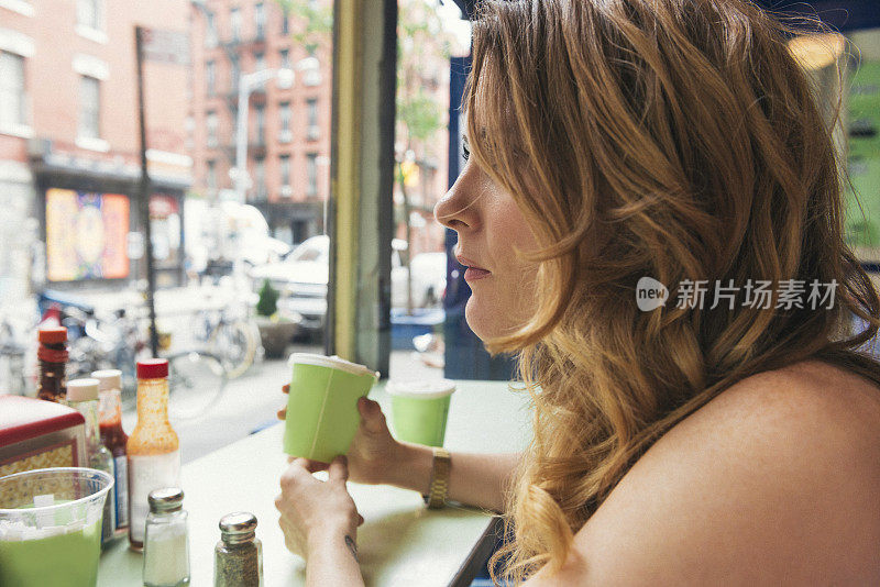 喝咖啡的纽约女人在咖啡馆餐厅向窗外看