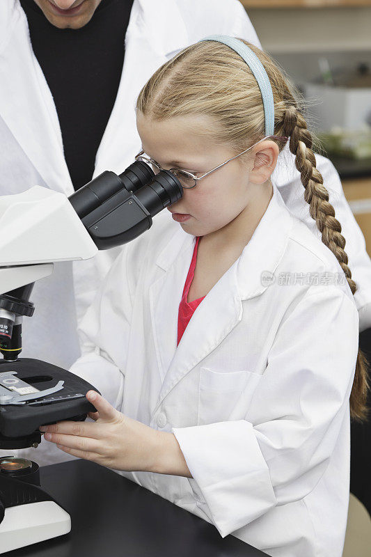 教师在实验室向年轻学生展示显微镜载玻片