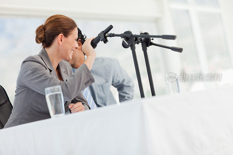 微笑的女商人在新闻发布会上盖住了麦克风