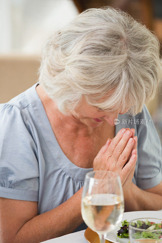 一个年长女人在饭前祷告的特写