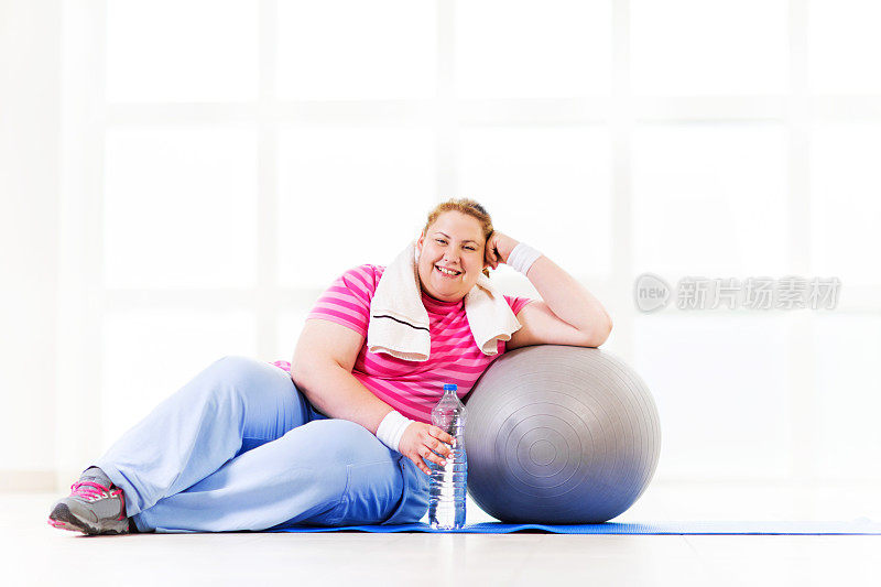 超重的女人在健身球上休息。