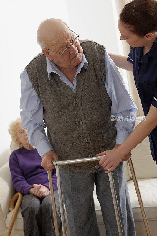 年轻的护士协助一位老人使用助行架