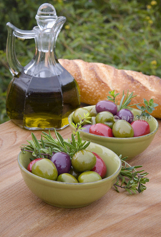 地中海食物;户外野餐桌上放橄榄、面包和橄榄油