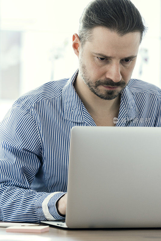 一名记者穿着衬衫在笔记本电脑上工作的肖像