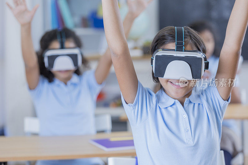 一组学生在使用虚拟现实眼镜时举手