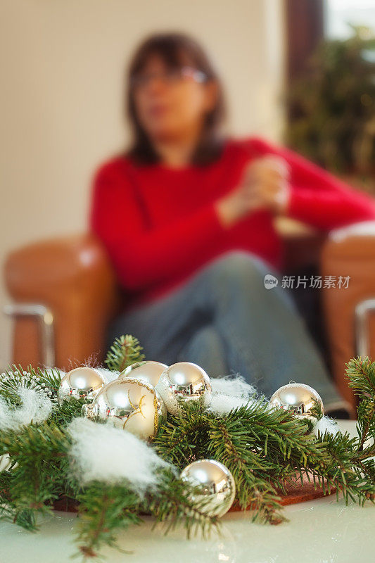 独自坐在圣诞装饰品后面的女人